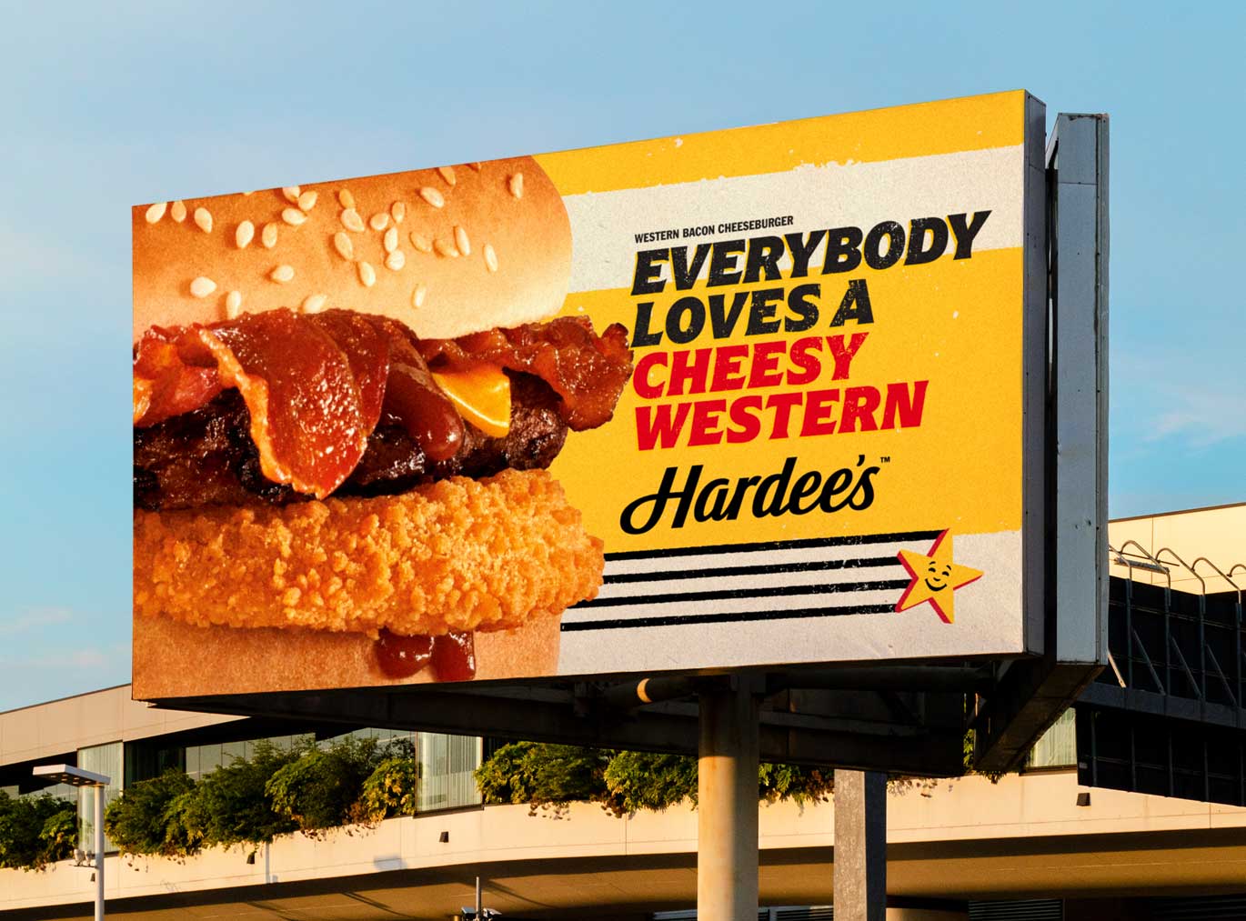 Billboard with a burger and the wordmark ‘Everybody loves a cheesy Western’ set in Arpona Italic and the Hardee's logo